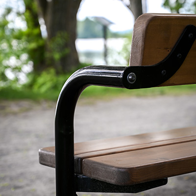 A close up shot of a black metal arm rest on a park bench.